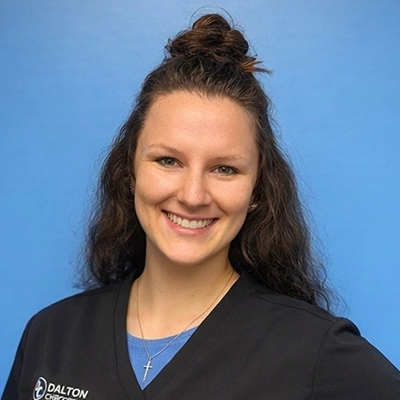 Chiropractor Tyler Bieszczad Smiling In Front Of Blue Background